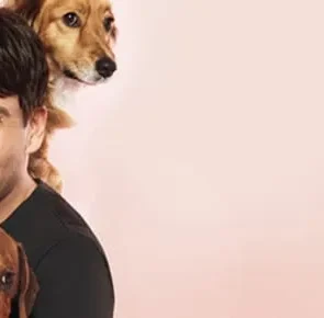 Celebrity Peter Alexander smiling while holding his beloved dachshund Penny and a fluffy dog.