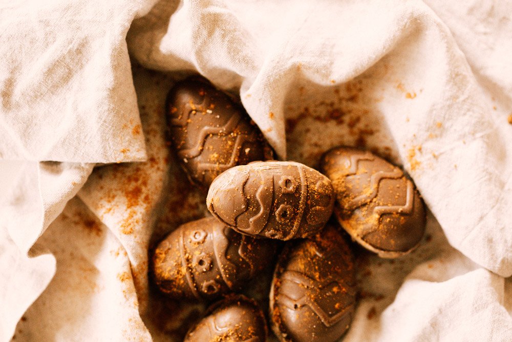 Homemade carob Easter eggs for dogs with decorative patterns on a linen cloth for a DIY dog treat recipe.