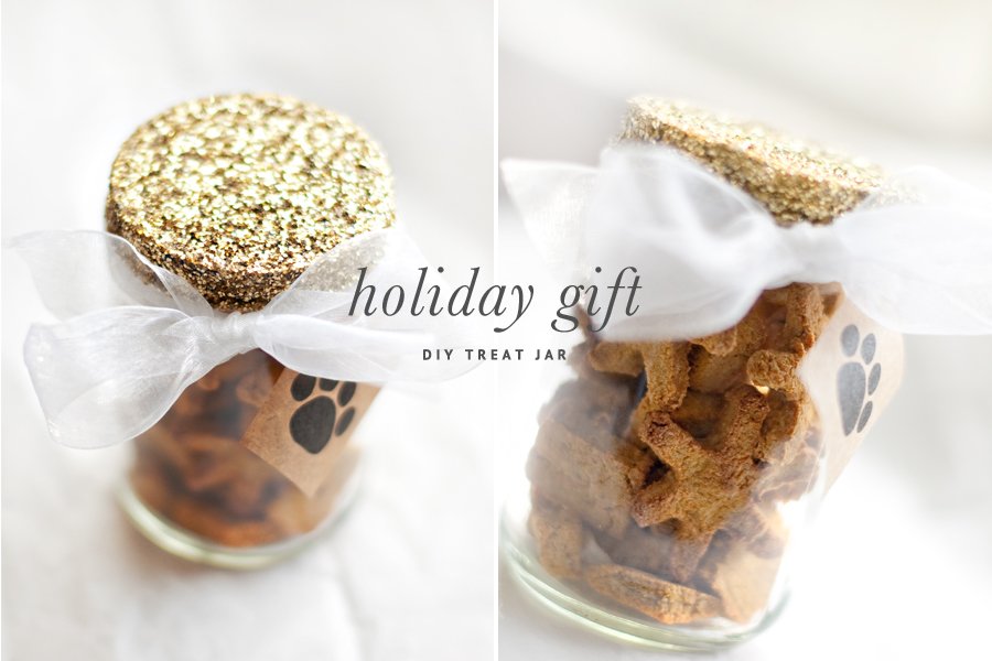 DIY holiday dog treat jar with a gold glitter lid, white ribbon, and paw print tag, filled with homemade dog treats.