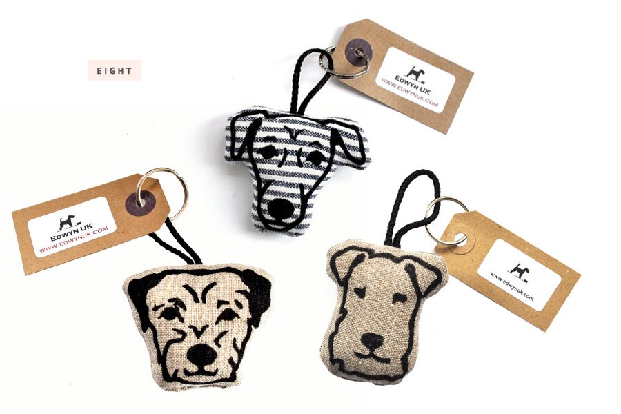 Handmade plush dog head keychains by Edwyn UK with embroidered breed faces on linen and striped fabric.
