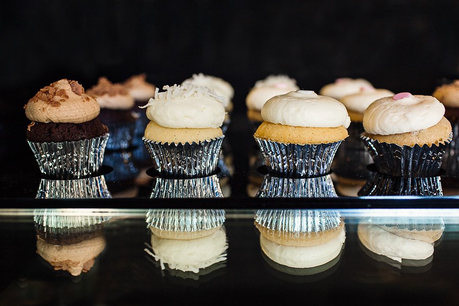 Assorted gourmet cupcakes with silver liners on display at Sparkle Cupcakery.