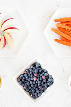 Fresh apples, carrots, and blueberries in bowls, perfect healthy ingredients for DIY dog treats and pet wellbeing.