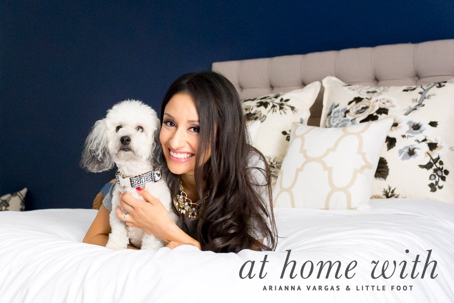 Arianna Vargas and her small white dog Little Foot posing on a bed for a pet-friendly lifestyle home tour.