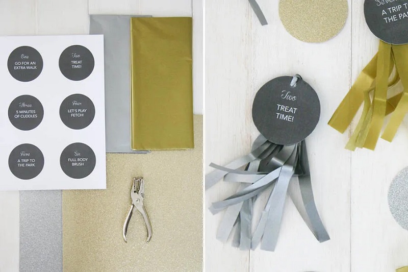 DIY reverse advent calendar materials with dog activity tags, gold and silver tissue paper, and a hole punch.