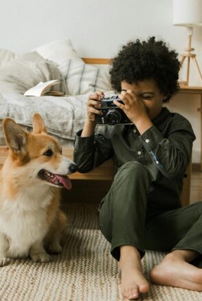 Young boy photographing his pet Corgi dog, showing the companionship and amazing benefits of dogs for kids.