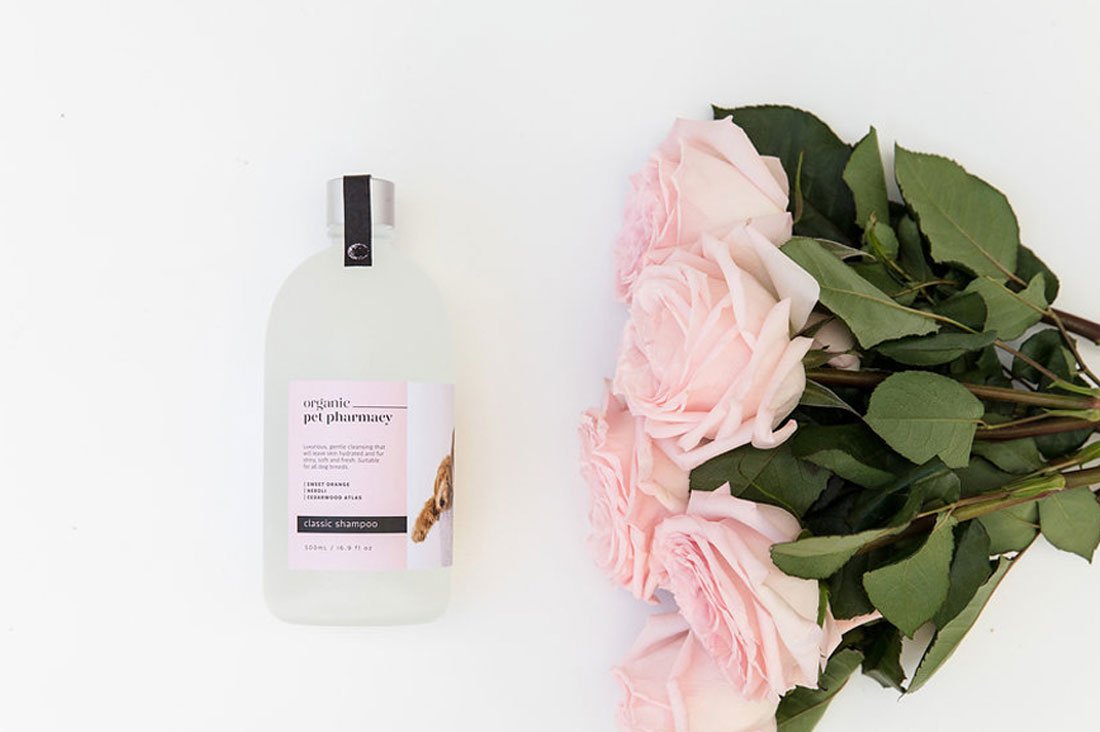 Organic Pet Pharmacy classic dog shampoo for sensitive skin next to pink roses on a white background.