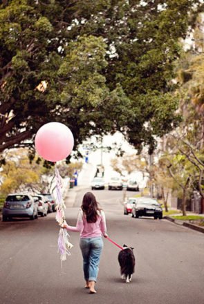 Woman walking her dog with a large pink balloon, symbolizing a farewell and new beginnings for Pretty Fluffy.