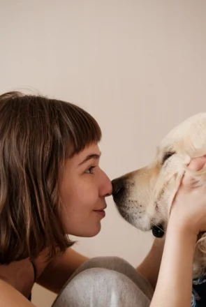 Happy dog mum touching noses with her golden retriever, celebrating a sweet moment with her four-legged mate.