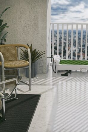 Fydoo self-cleaning dog toilet with synthetic grass installed on a modern apartment balcony with outdoor furniture.