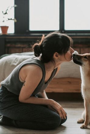 Woman kneeling on the floor kissing her Shiba Inu's nose, illustrating dog love for inspirational dog captions.