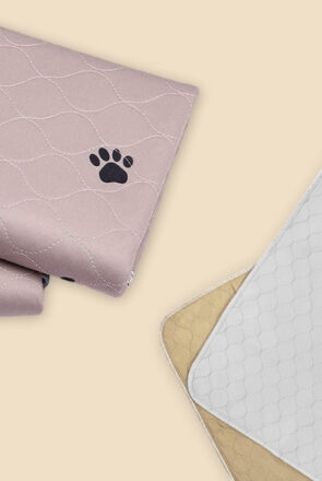 Washable pee pads for dogs in pink with paw prints and white quilted reusable training mats.