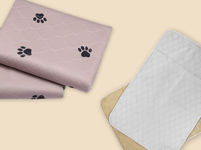 Washable pee pads for dogs in pink with paw prints and white quilted reusable training mats.