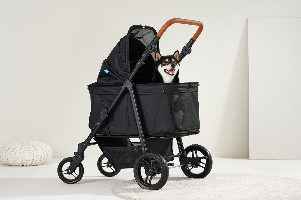 Happy Shiba Inu dog sitting inside a modern black dog stroller with a brown leather handle.